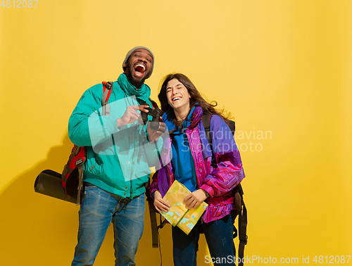 Image of Portrait of a cheerful young tourist couple isolated on yellow background