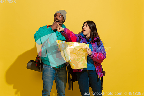 Image of Portrait of a cheerful young tourist couple isolated on yellow background