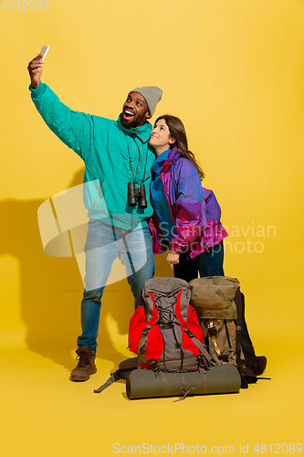 Image of Portrait of a cheerful young tourist couple isolated on yellow background