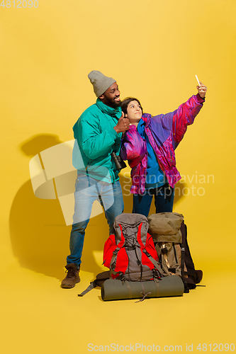Image of Portrait of a cheerful young tourist couple isolated on yellow background