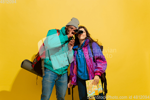 Image of Portrait of a cheerful young tourist couple isolated on yellow background