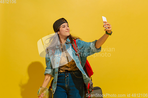 Image of Portrait of a cheerful young caucasian tourist girl isolated on yellow background