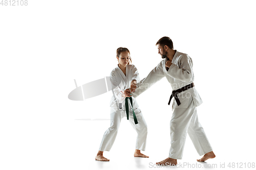 Image of Junior in kimono practicing hand-to-hand combat with coach, martial arts