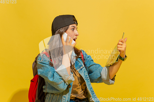 Image of Portrait of a cheerful young caucasian tourist girl isolated on yellow background