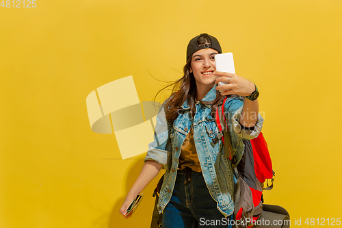 Image of Portrait of a cheerful young caucasian tourist girl isolated on yellow background