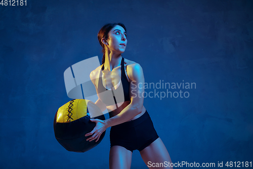 Image of Caucasian young female athlete practicing on blue studio background in neon light