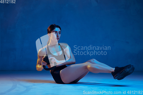 Image of Caucasian young female athlete practicing on blue studio background in neon light