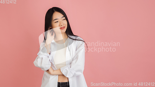 Image of Asian young woman\'s portrait on pink studio background. Concept of human emotions, facial expression, youth, sales, ad.