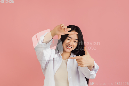 Image of Asian young woman\'s portrait on pink studio background. Concept of human emotions, facial expression, youth, sales, ad.