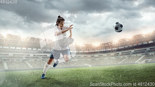 Image of Male soccer, football player catching ball in jump at the stadium during sport match on dark sky background