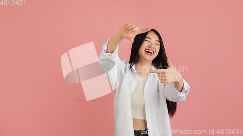 Image of Asian young woman\'s portrait on pink studio background. Concept of human emotions, facial expression, youth, sales, ad.