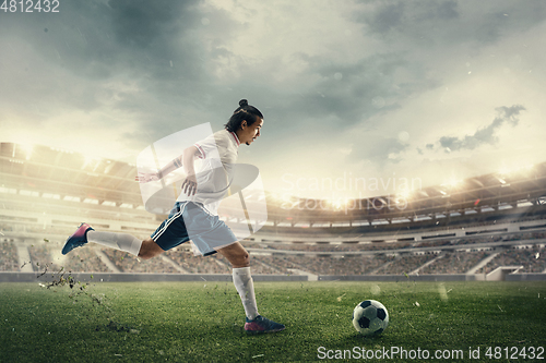 Image of Male soccer, football player catching ball in jump at the stadium during sport match on dark sky background