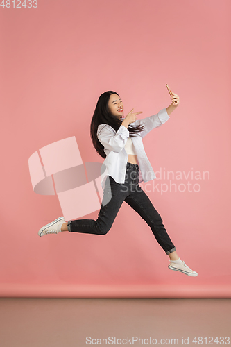 Image of Asian young woman\'s portrait on pink studio background. Concept of human emotions, facial expression, youth, sales, ad.