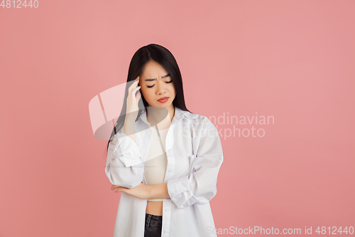 Image of Asian young woman\'s portrait on pink studio background. Concept of human emotions, facial expression, youth, sales, ad.