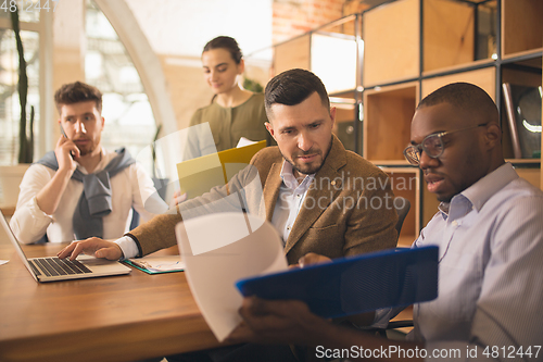 Image of Colleagues working together in modern office using devices and gadgets during creative meeting