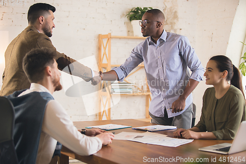 Image of Colleagues working together in modern office using devices and gadgets during creative meeting