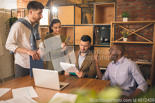 Image of Colleagues working together in modern office using devices and gadgets during creative meeting