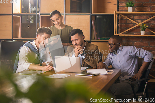 Image of Colleagues working together in modern office using devices and gadgets during creative meeting