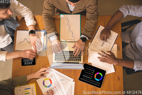 Image of Top view, close up. Colleagues working together in modern office using devices and gadgets during creative meeting