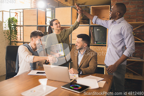 Image of Colleagues working together in modern office using devices and gadgets during creative meeting