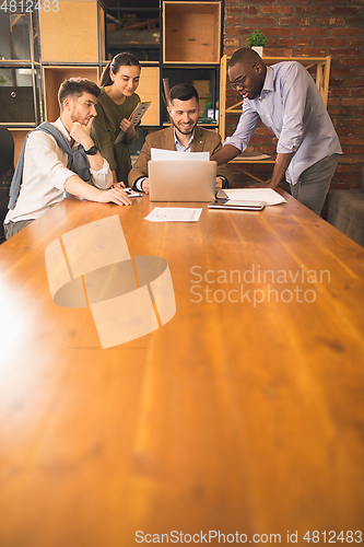 Image of Colleagues working together in modern office using devices and gadgets during creative meeting