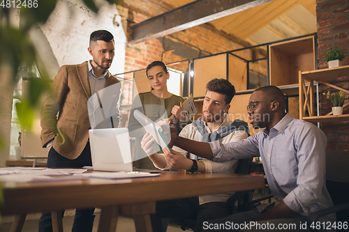 Image of Colleagues working together in modern office using devices and gadgets during creative meeting