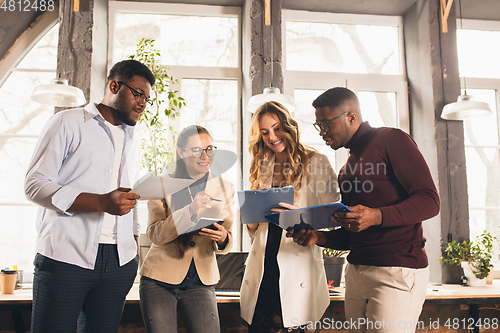 Image of Colleagues working together in modern office using devices and gadgets during negotiations