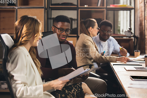 Image of Colleagues working together in modern office using devices and gadgets during negotiations