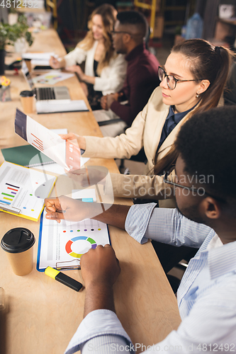 Image of Colleagues working together in modern office using devices and gadgets during negotiations