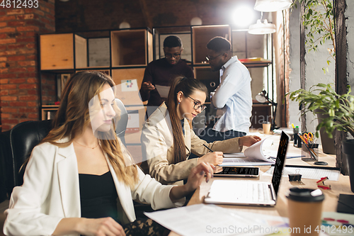 Image of Colleagues working together in modern office using devices and gadgets during negotiations