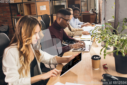 Image of Colleagues working together in modern office using devices and gadgets during negotiations