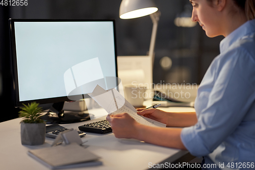 Image of businesswoman with papers working at night office