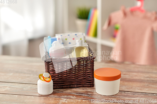 Image of baby things in basket on wooden table at home