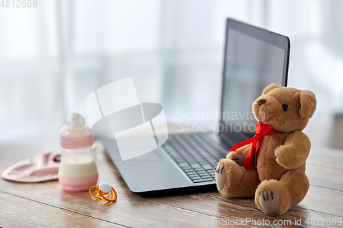 Image of baby milk formula, laptop, soother and teddy bear