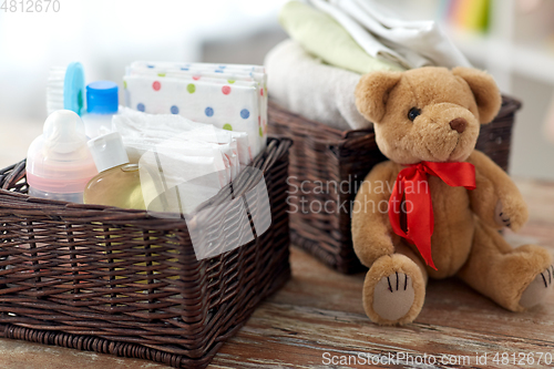 Image of baby things in baskets and teddy bear toy on table