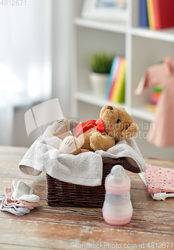 Image of teddy bear toy in basket with baby things on table