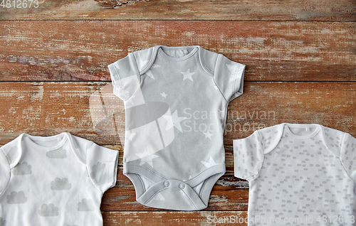 Image of baby clothes set of bodysuits on wooden table