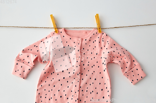 Image of bodysuit for baby girl hanging on rope with pins