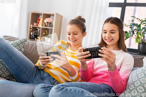 Image of happy teenage girls with smartphones at home