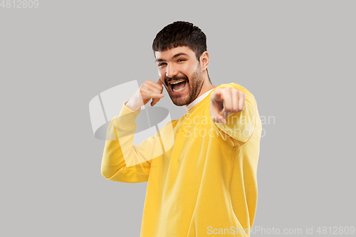 Image of man making phone call gesture and pointing finger