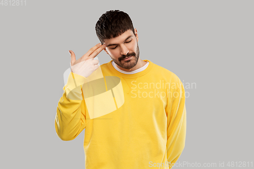 Image of bored man making finger gun gesture