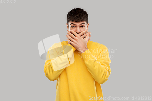 Image of shocked young man covering his mouth with hands