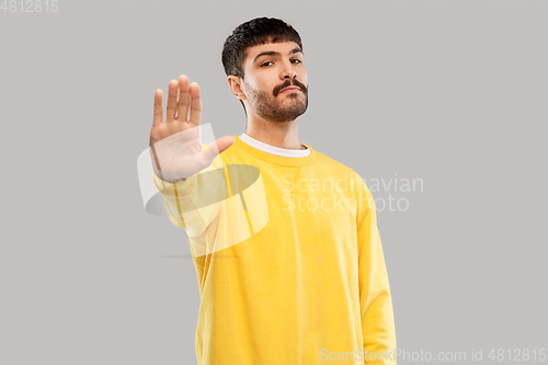 Image of serious young man showing stop gesture