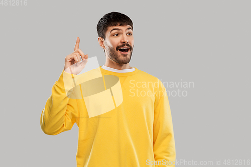 Image of young man showing one finger in yellow sweatshirt