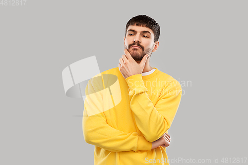 Image of thinking young man in yellow sweatshirt