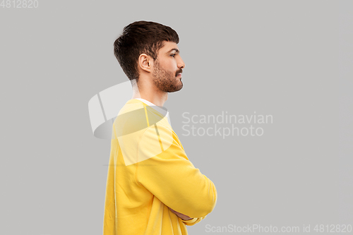 Image of young man in yellow sweatshirt with crossed arms