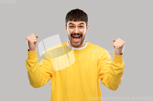 Image of happy man in yellow sweatshirt celebrating victory