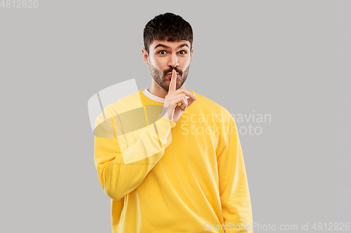 Image of young man making hush gesture with finger on lips