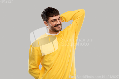 Image of smiling young man in glasses and yellow sweatshirt