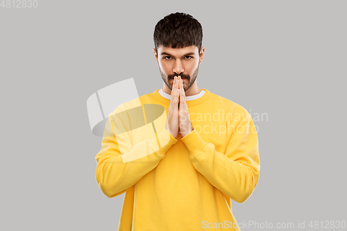 Image of man in yellow sweatshirt praying or giving thanks